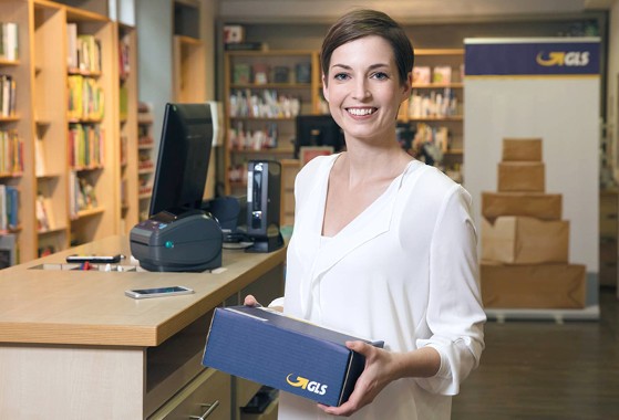 Femme souriant tient colis GLS France dans bureau dépôt