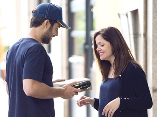 Chauffeur GLS France donne colis cliente souriante